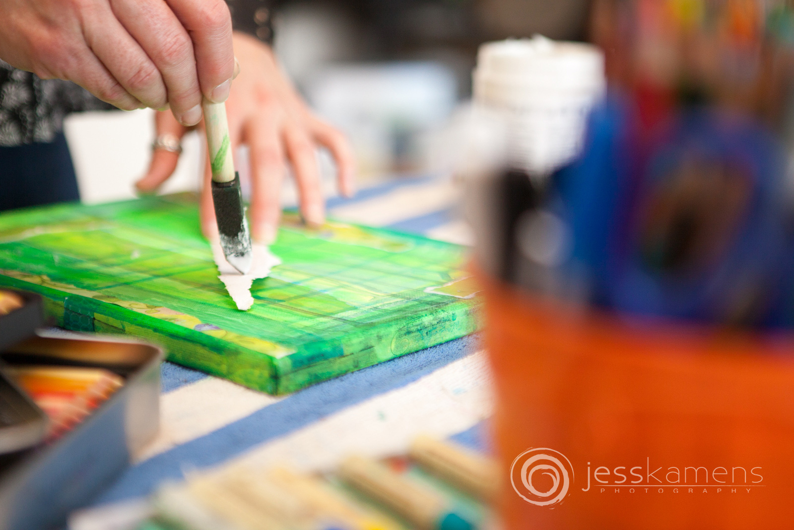 An artist using a collage technique with torn paper and modge podge