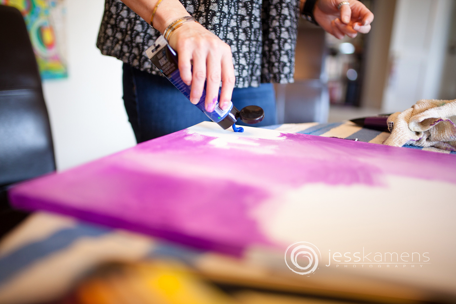a woman pouring blue paint onto her painting