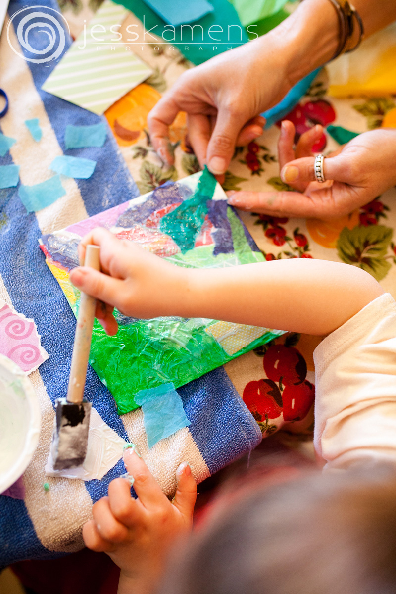 a woman's hands and a child's hands making art