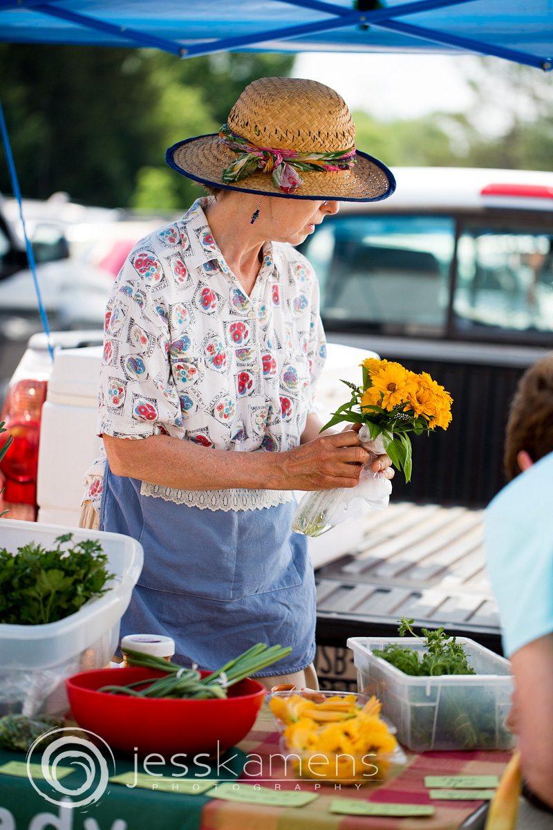 a woman holding yellow flowers and wearing a sun hat