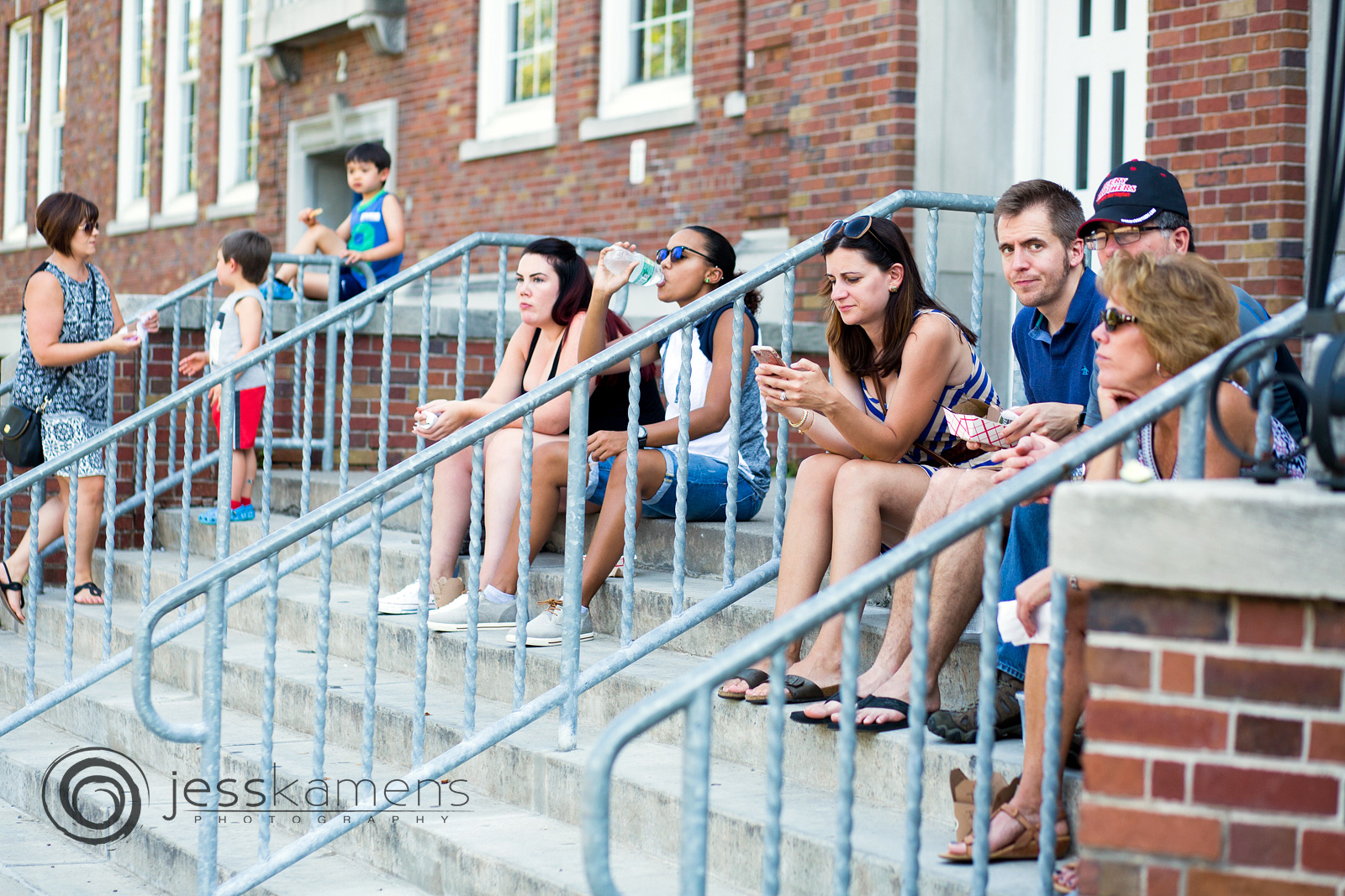 people sit on the steps of Brighton High School and enjoy the market on Sunday morning