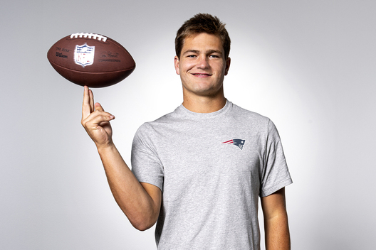 Portrait of New England Patriots quarterback, Drake Maye spinning a football