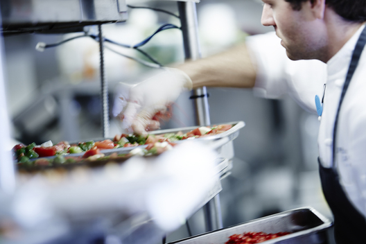 Photographer Jessica Gernier took a lifestyle food photography image in the kitchen of a busy restaurant showcasing a chef prepping dishes at a high-end restaurant in Aspen, Colorado. 